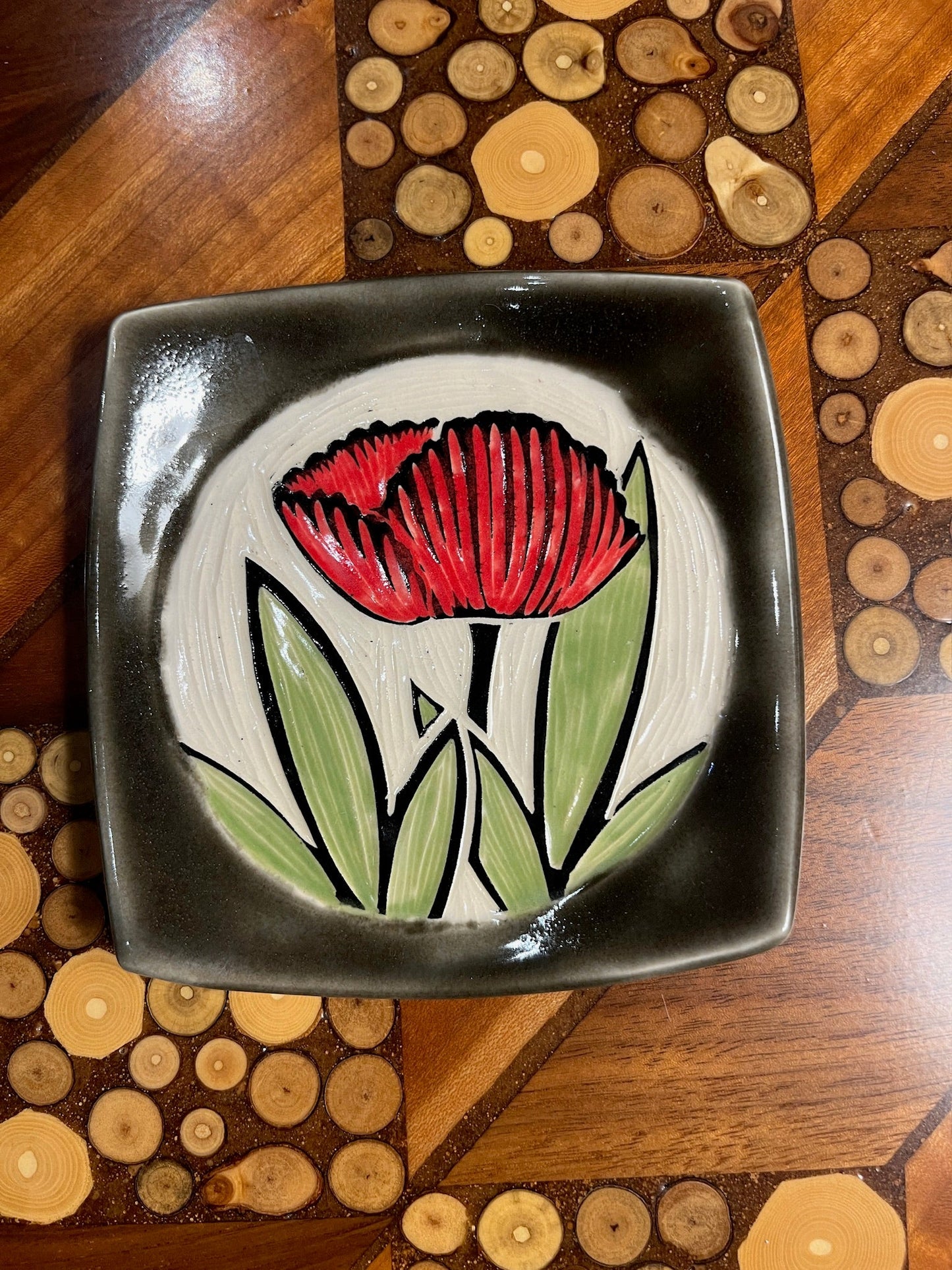 Ceramic dish with a red flower design on a wooden surface