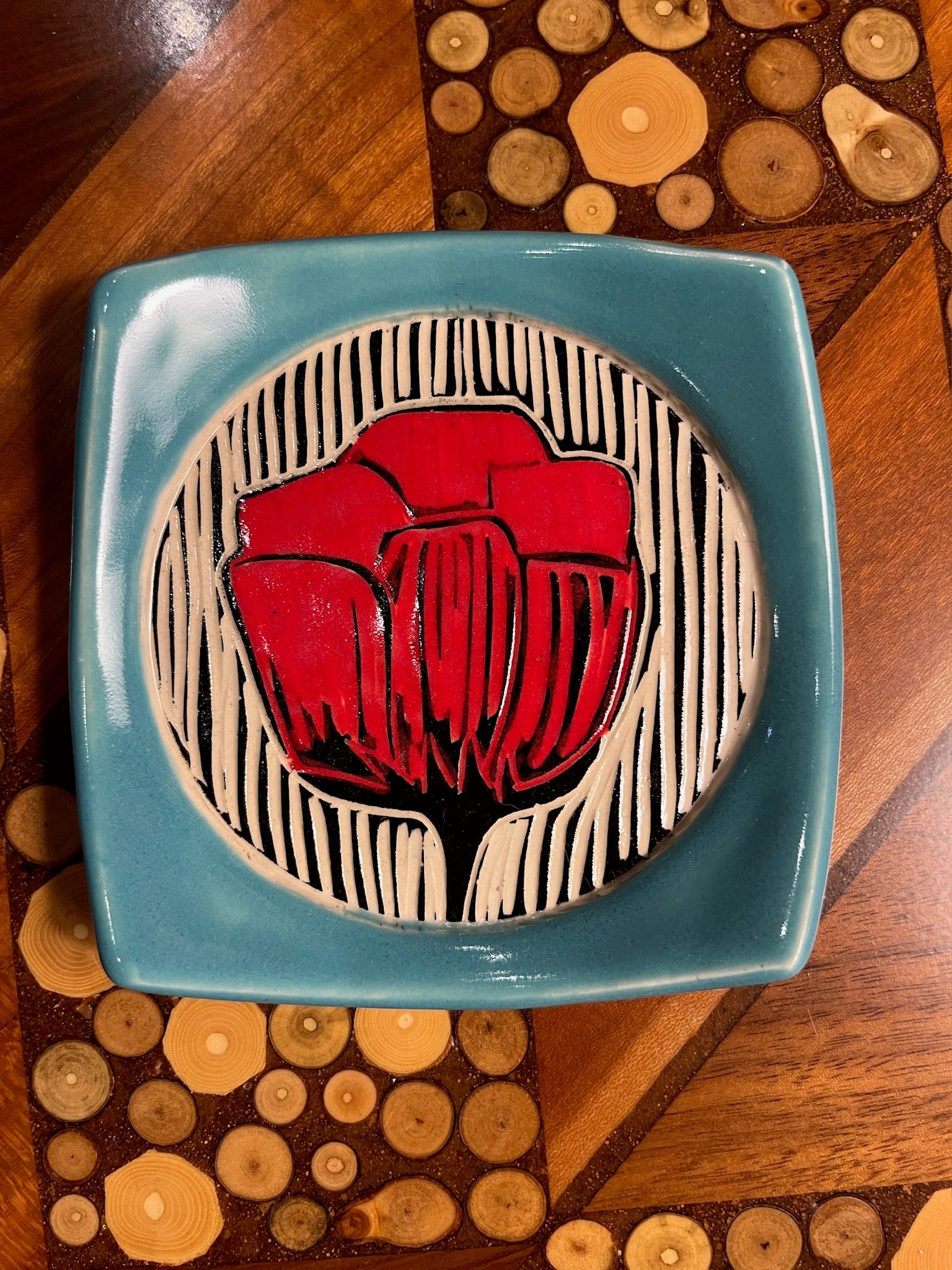 Ceramic plate with red floral design on a wooden surface