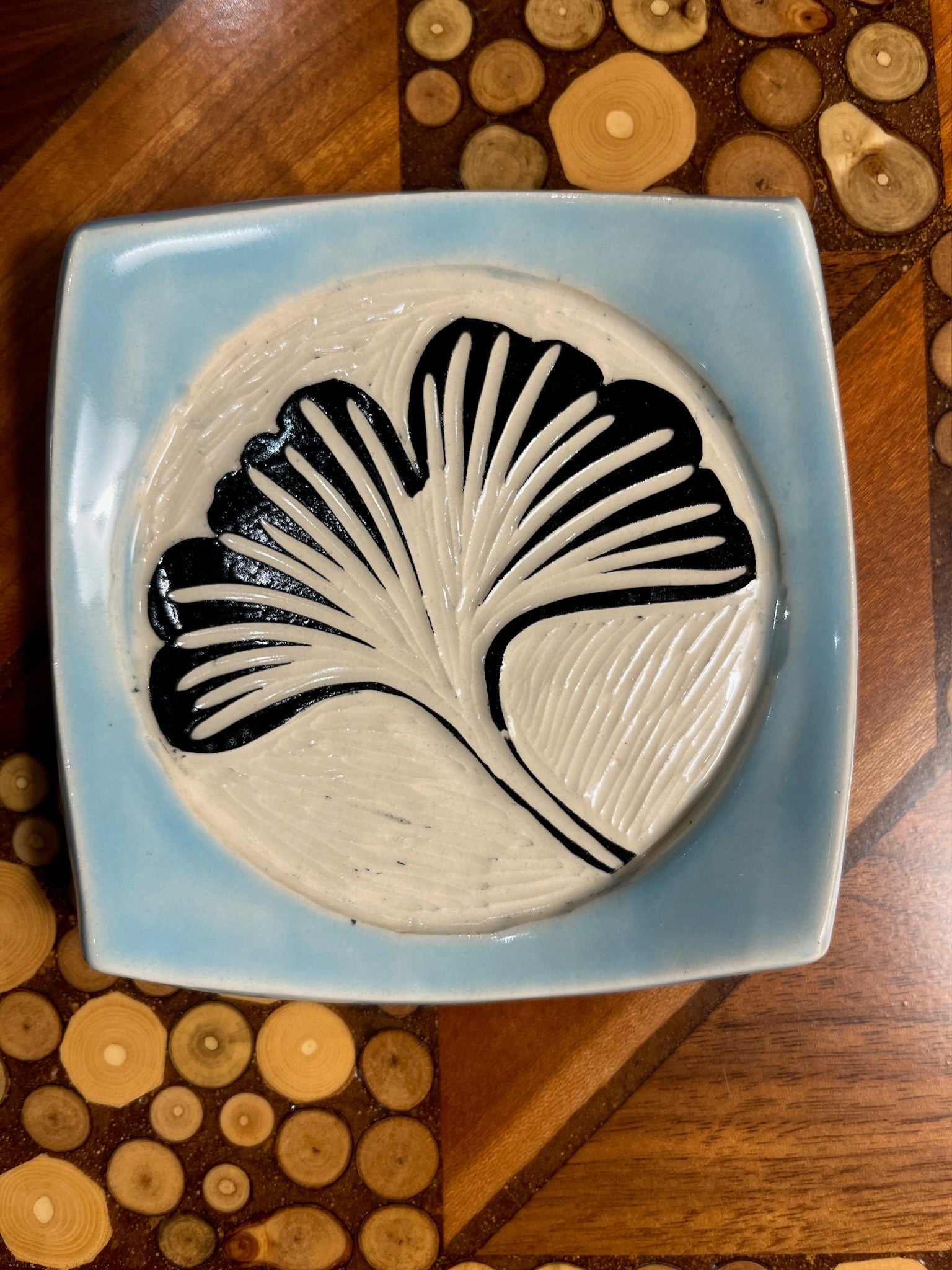 Ceramic plate with black leaf design on a light blue background