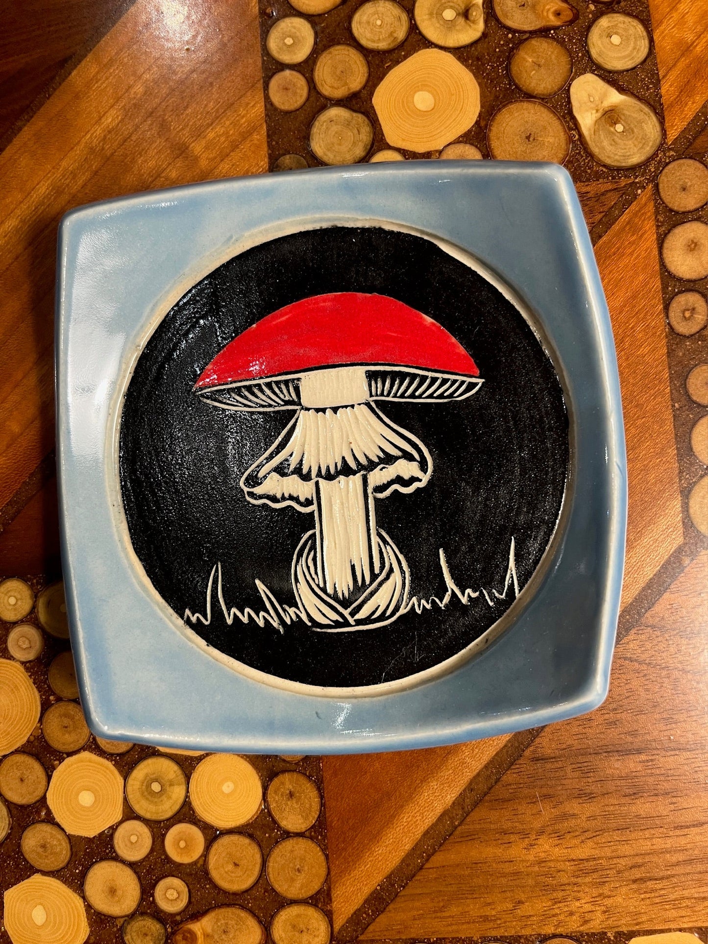 Decorative plate with a mushroom design on a wooden surface