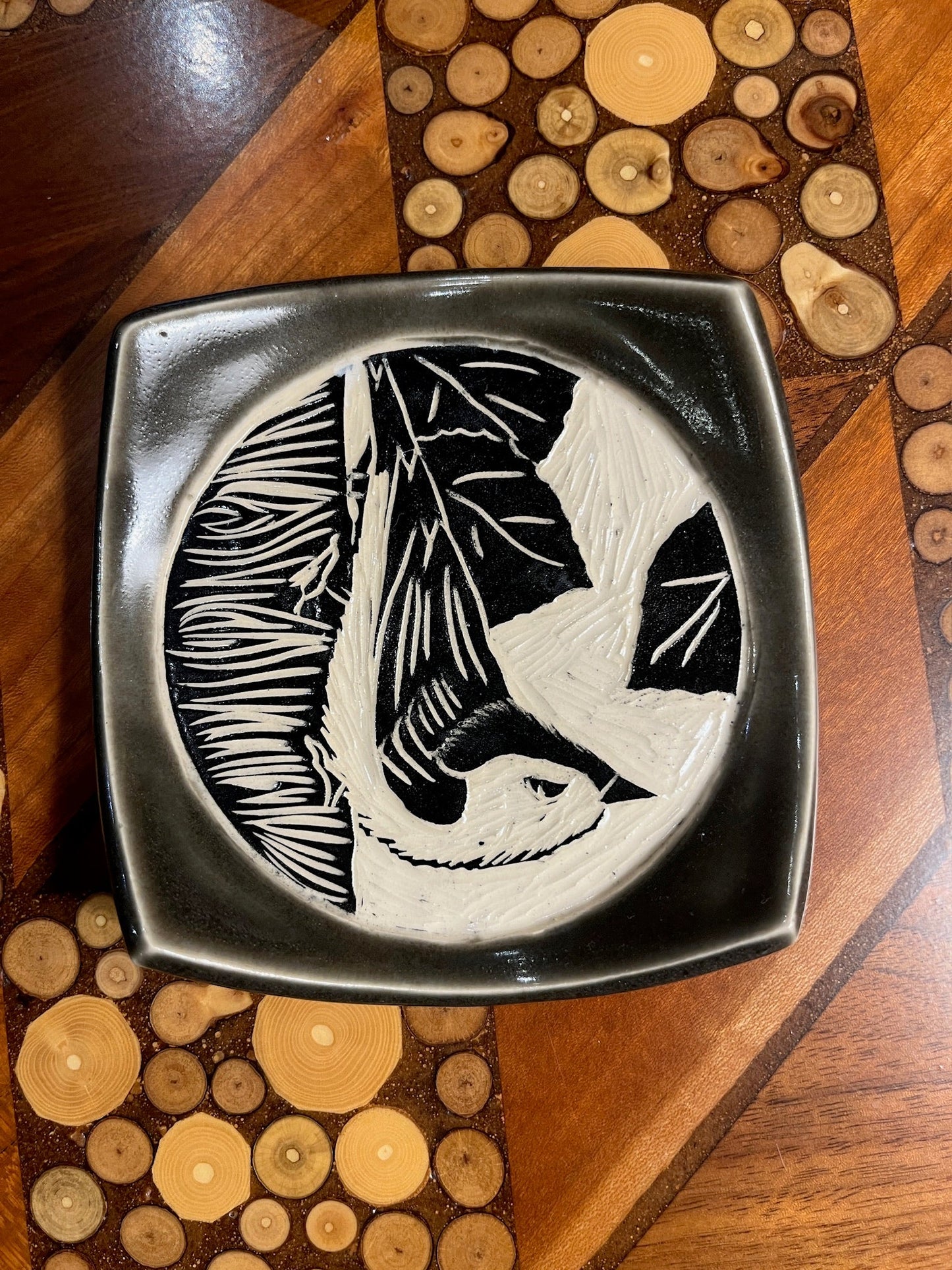 Decorative plate with a bird design on a wooden surface