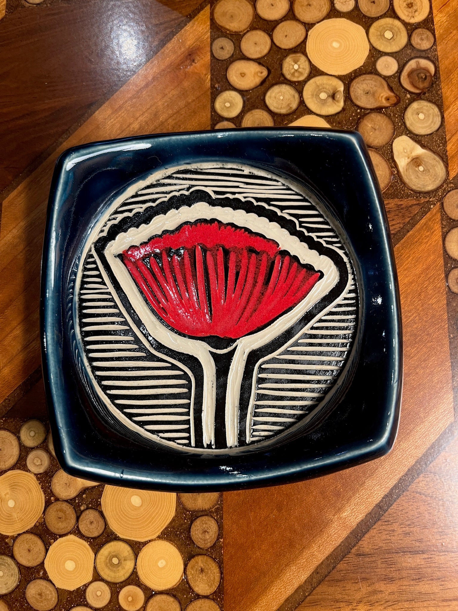 Decorative bowl with a red and black design on a wooden surface